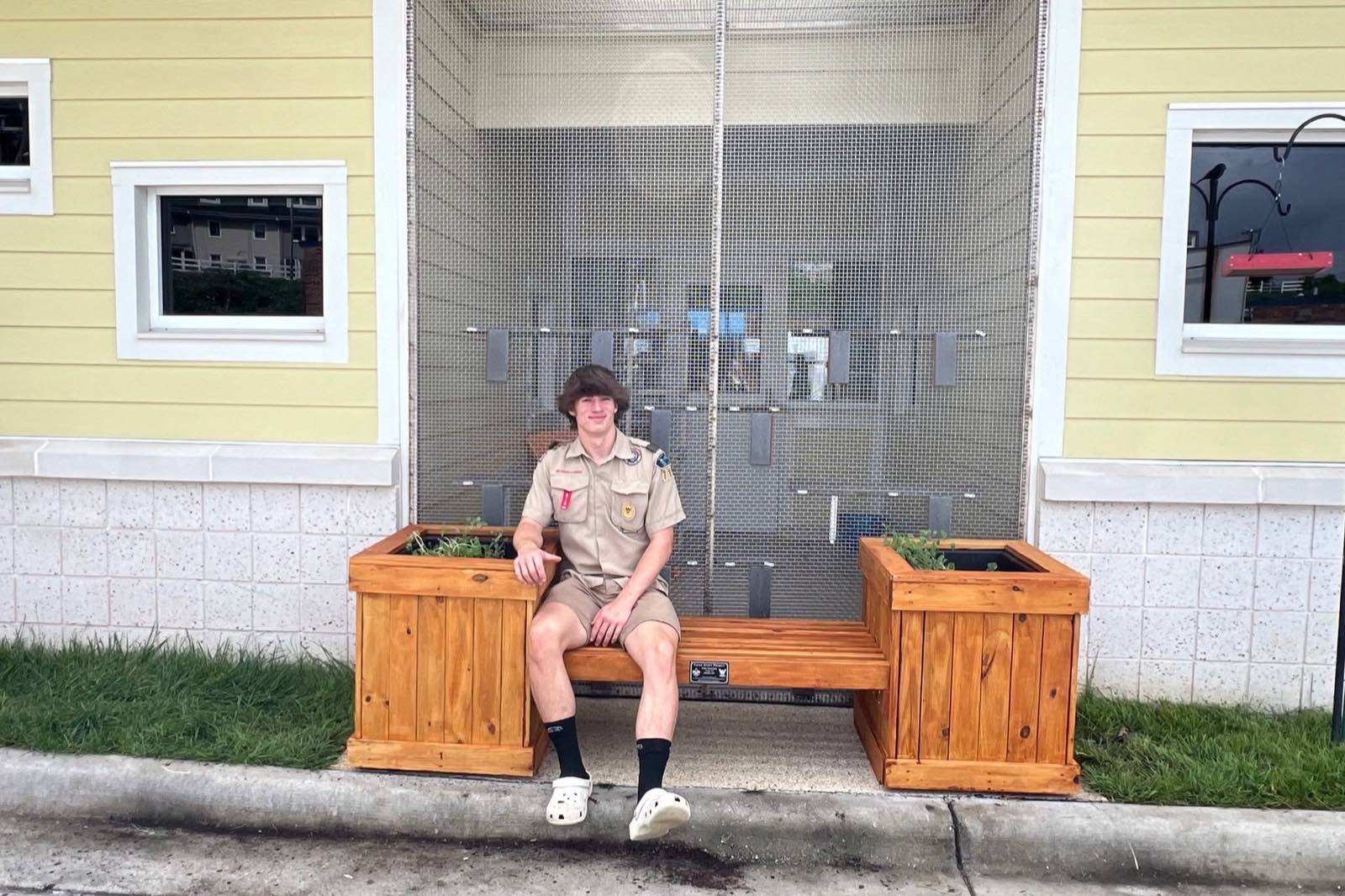 John Jacobson in Scout uniform sitting on one of the finished planter benches he built for the Forsyth County Humane Society.
